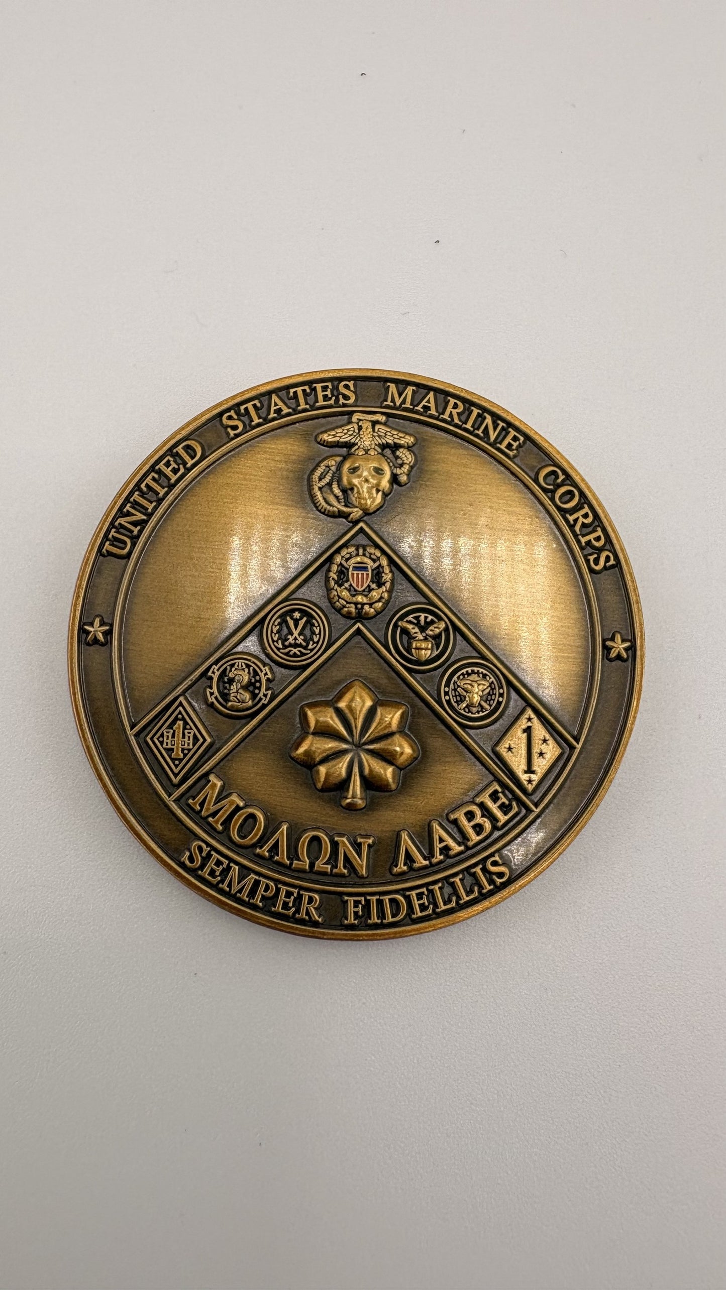 Antique-bronze challenge coin struck in 3D relief with no enamel fill, showing a United States Marine Corps emblem and crossed rifles