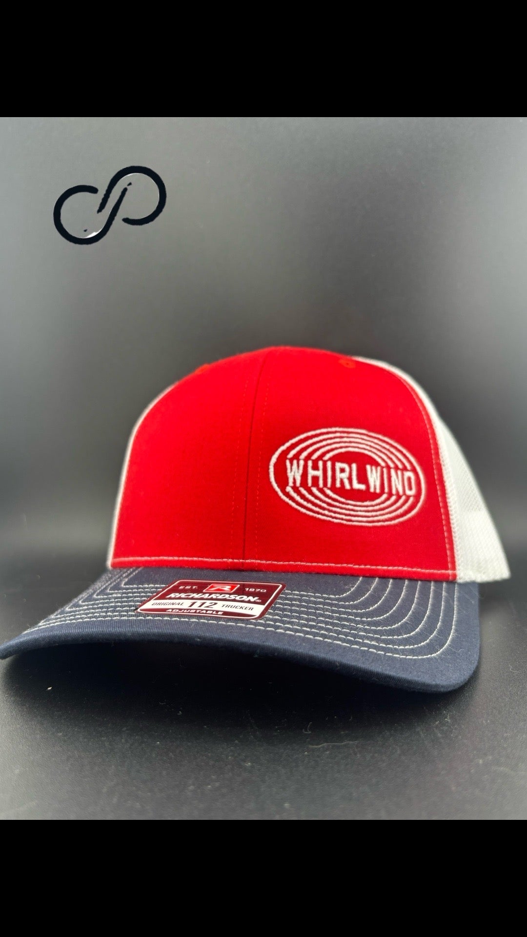 Red, white and navy trucker cap with an oval WHIRLWIND logo embroidered in white on the red front panel