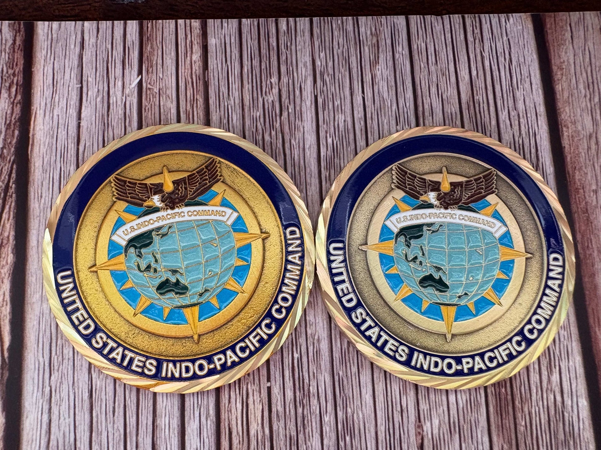 Two custom challenge coins face up side by side, the same die struck in bright gold and in antique gold, with a cut rope edge