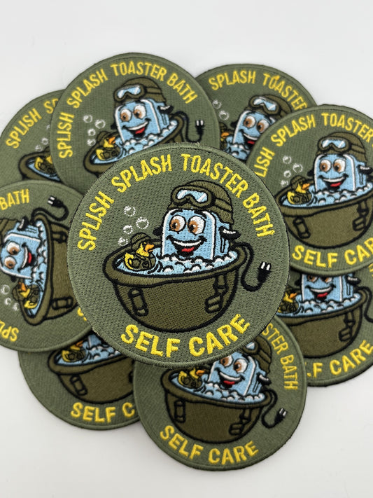Splish Splash Toaster Bath self-care morale patch — olive drab with yellow lettering, a toaster in a bathtub wearing a flight helmet